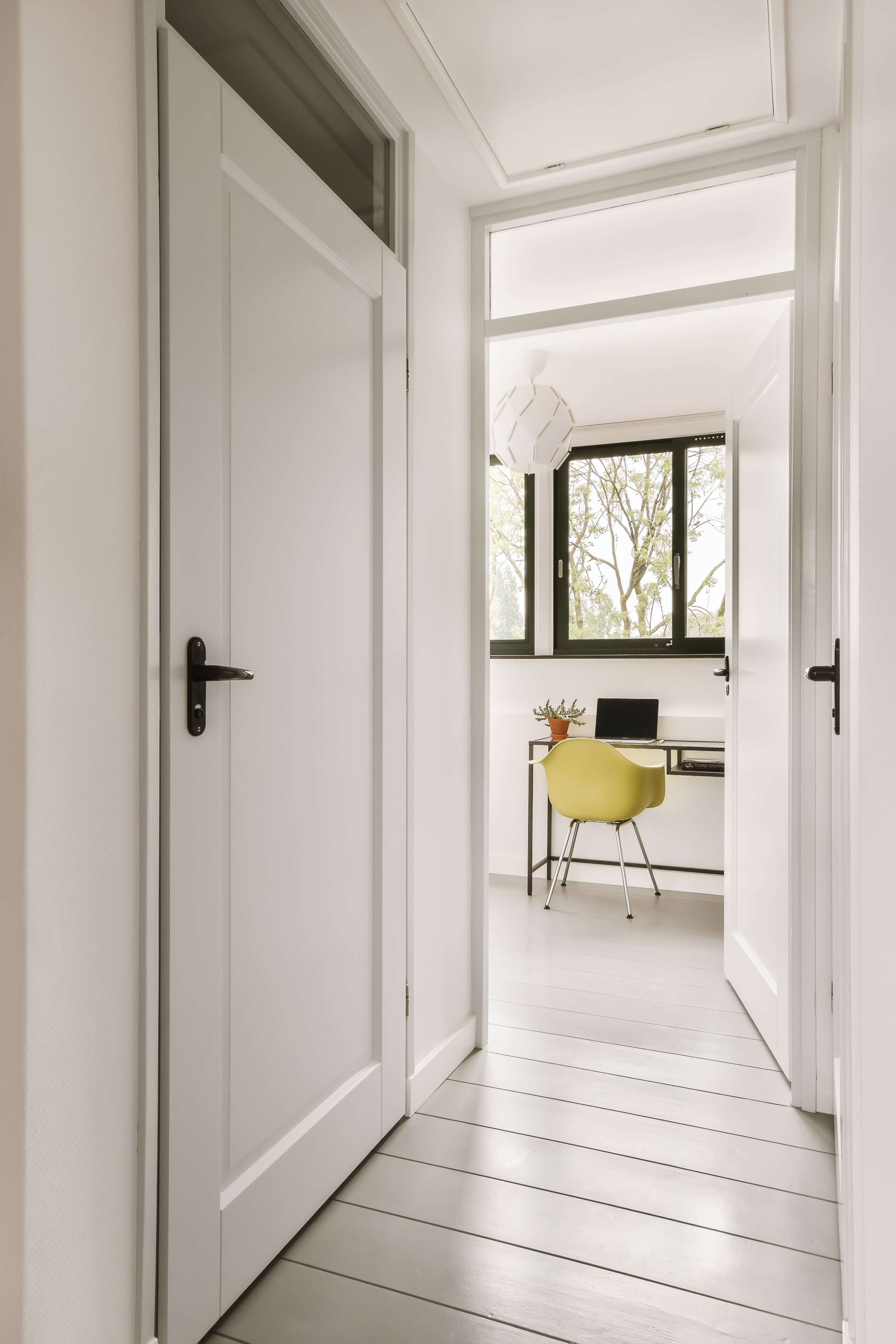 a hallway with a white door and a yellow chair