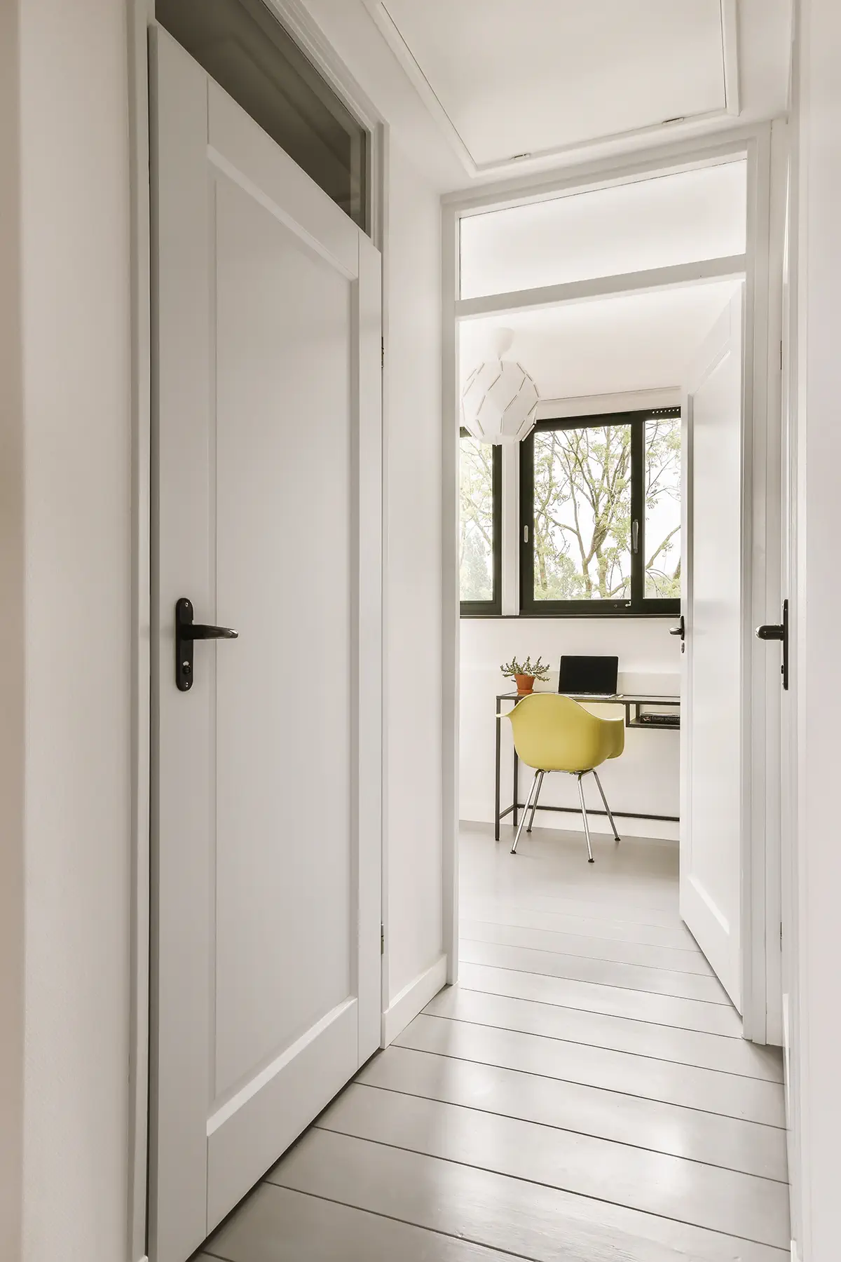 a hallway with a white door and a yellow chair